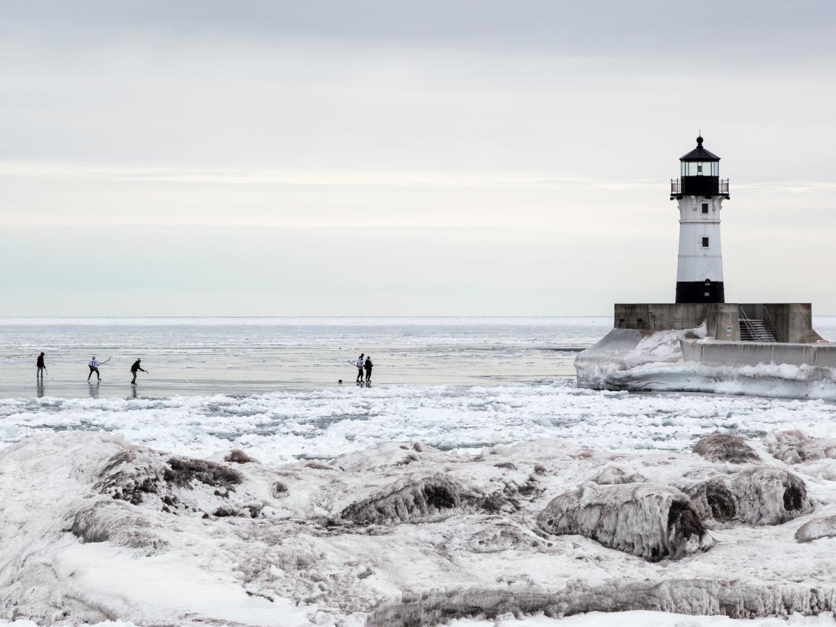 Playing ice hockey on Lake Superior with lighthouse in background